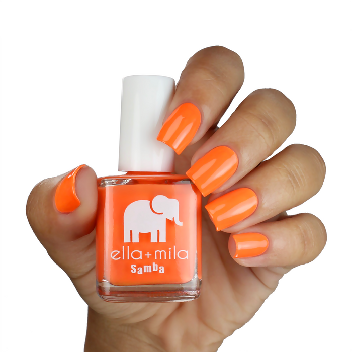 Cause I'm Happy neon orange nail polish on a medium skin tone, hand holding the bottle