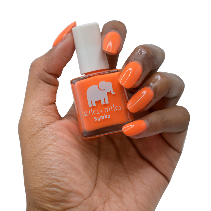 Cause I'm Happy neon orange nail polish on a deep skin tone, hand holding the bottle