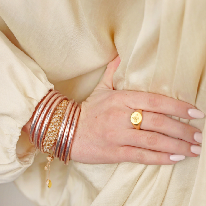 a hand with gold bracelets and a ring on it