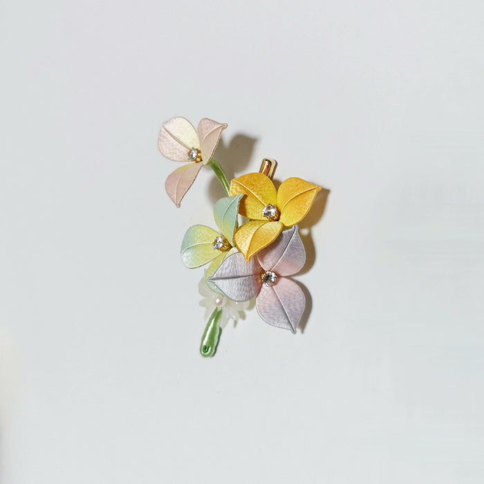 Chanhua Chunri handmade hydrangea hair clip with four pastel flowers in pink, yellow, mint green, and lavender, each with a crystal center, on a green stem with pearl bead, displayed on a light background