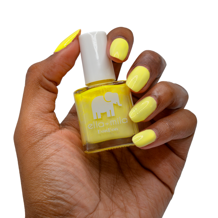 Copabikini yellow nail polish on a deep skin tone, hand holding the bottle