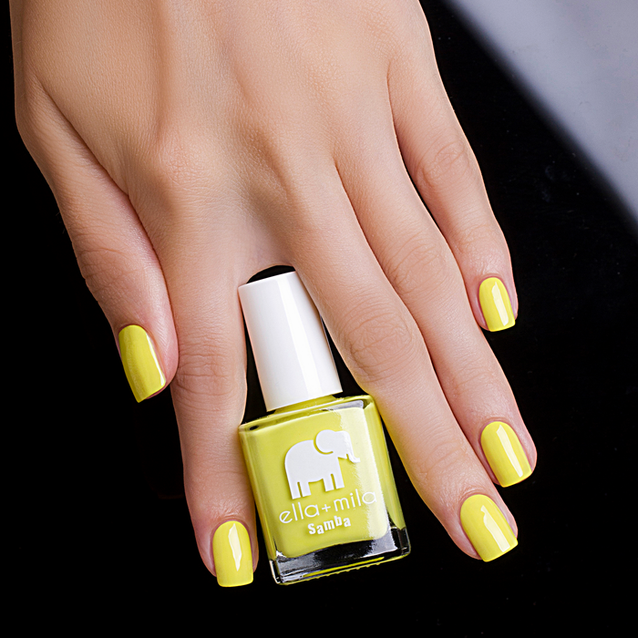 Copabikini neon yellow nail polish manicure holding the bottle