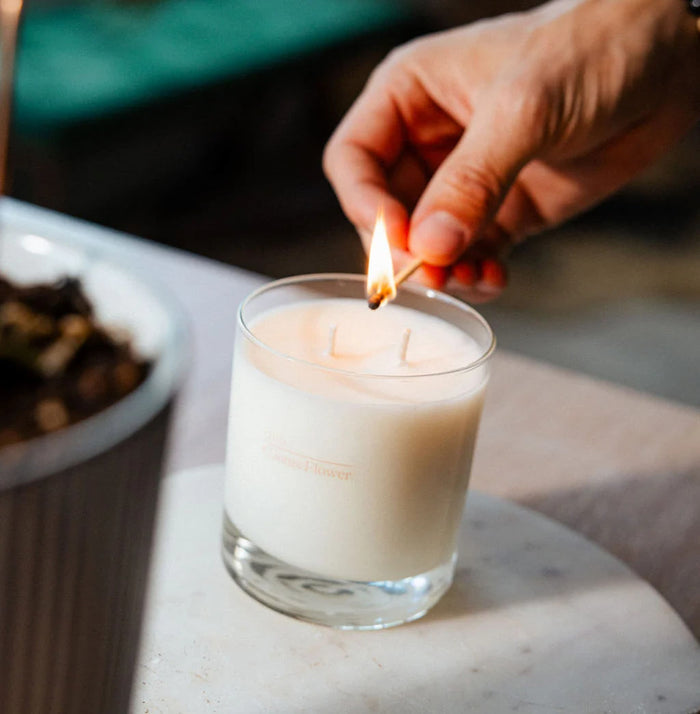 Hand lighting a candle with a match on a marble surface