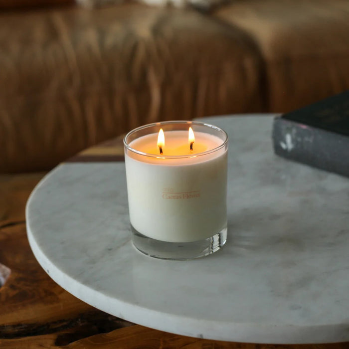 Candle in a glass container on a marble surface with a blurred background