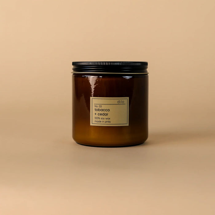 Brown candle with a black lid on a beige background