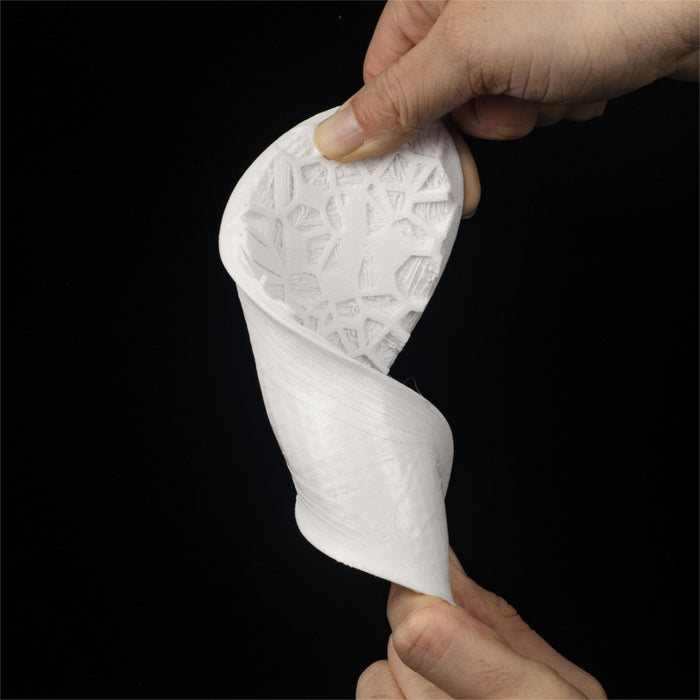 flexible TPU filament 85A white lattice print being twisted and stretched by two hands