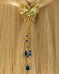 Gold butterfly hair hook ponytail holder with dangling blue crystal bead charms worn in blonde ponytail, back view