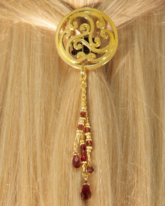 Gold Celtic circle hair hook with dangling red bead charms worn in ponytail, back view