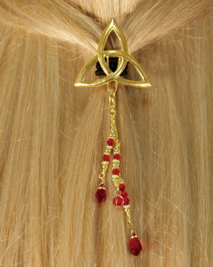 Back view of a model wearing a gold Celtic triquetra hair hook with dangling red bead charms securing a ponytail.