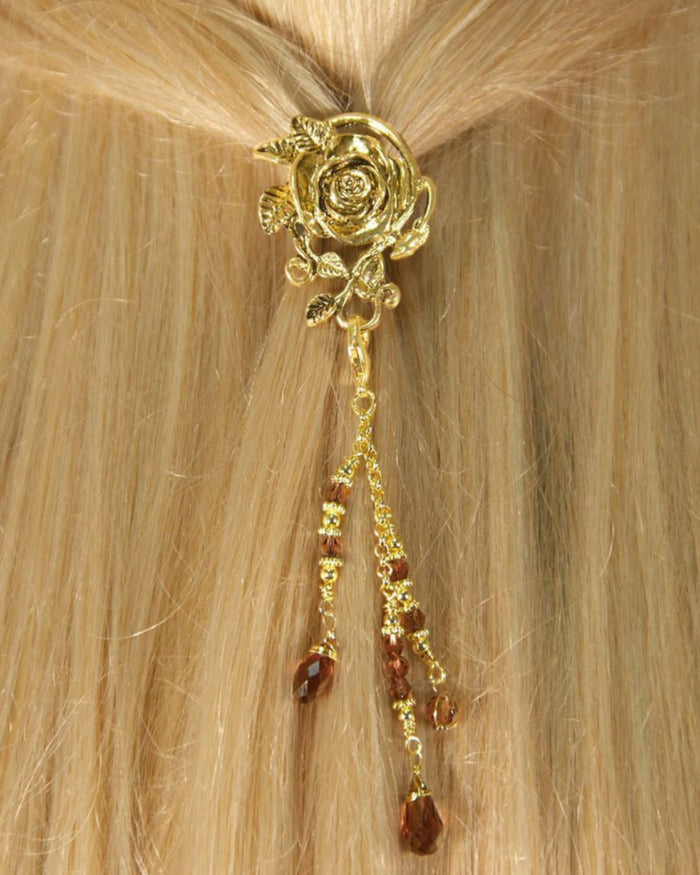 Model wearing a handcrafted gold rose hair hook with a dangling bead charm securing a ponytail by Medieval Metal.