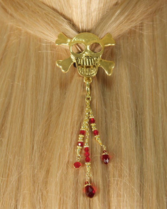 Model wearing a gold skull hair hook with dangling red bead charms securing a ponytail.