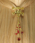 Model wearing a gold skull hair hook with dangling red bead charms securing a ponytail.