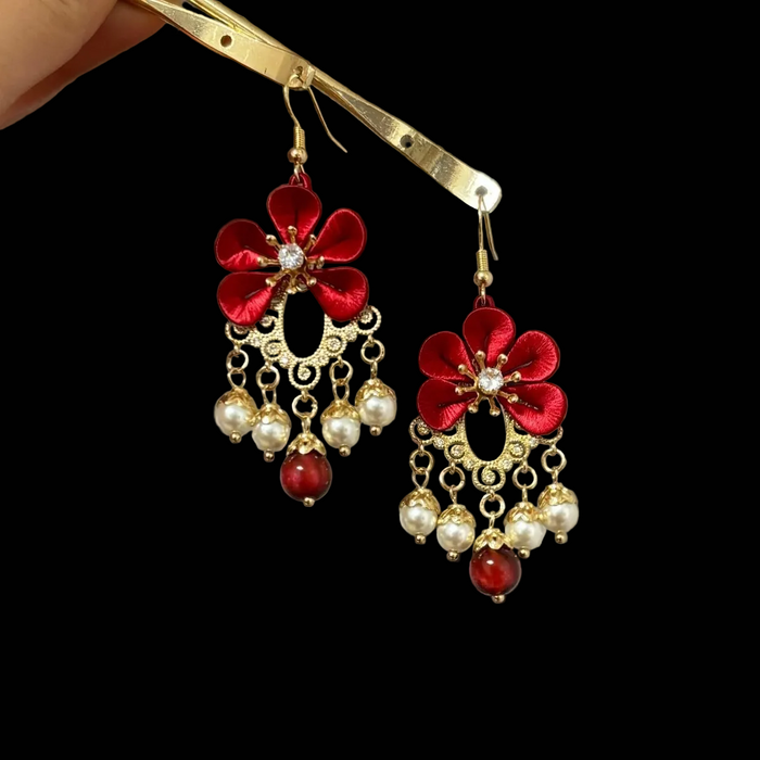Close-up of Chanhua red flower earring showing thread-wrapped red petals, crystal center, and gold filigree frame detail
