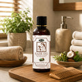 Herby Hair Oil bottle displayed in a warm bathroom setting with towels, greenery and natural wooden accessories.