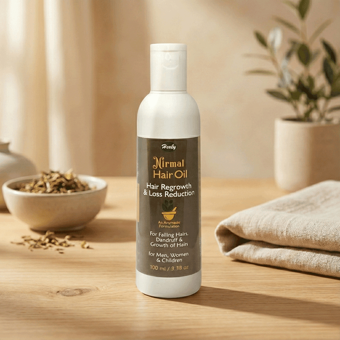Herby Nirmal Hair Oil bottle displayed in a warm natural setting with a wooden bowl, folded towel and greenery.