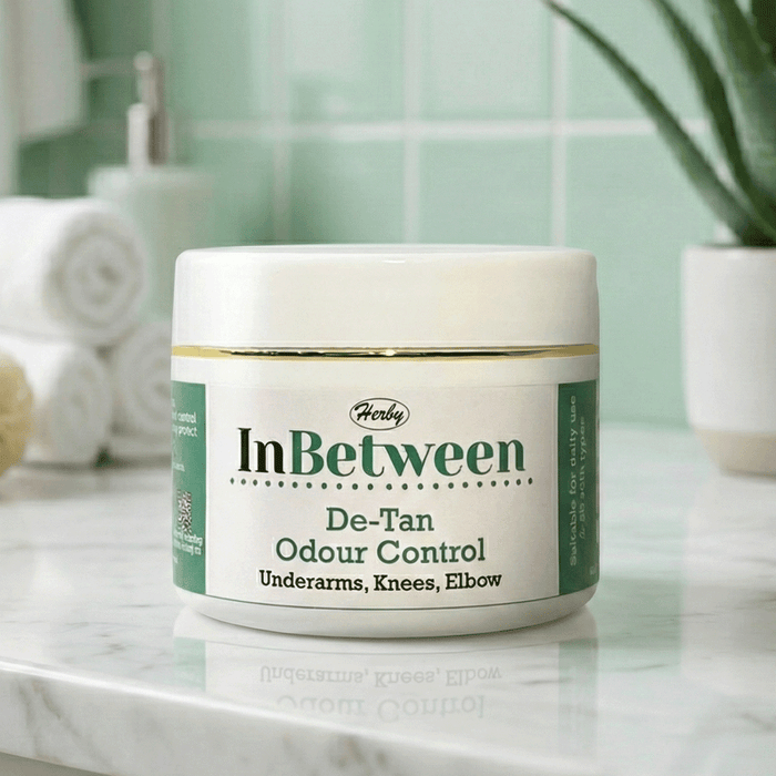 Herby InBetween De-Tan cream jar displayed in a clean bathroom setting with soft green tiles and minimal decor.
