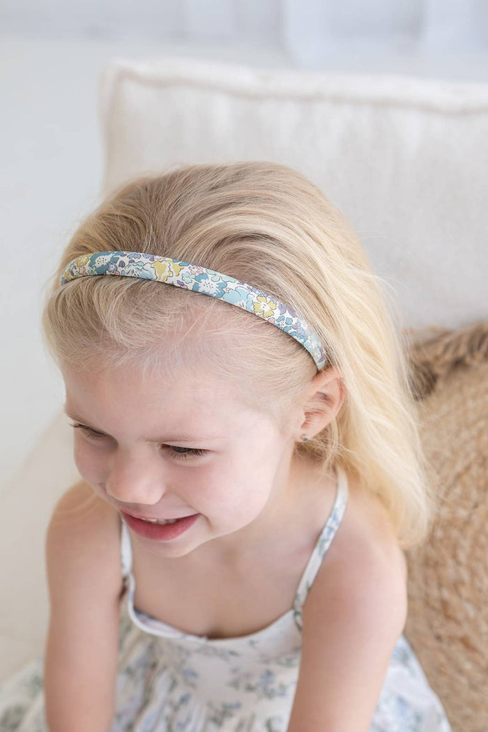 Young girl wearing a floral headband with on a light background