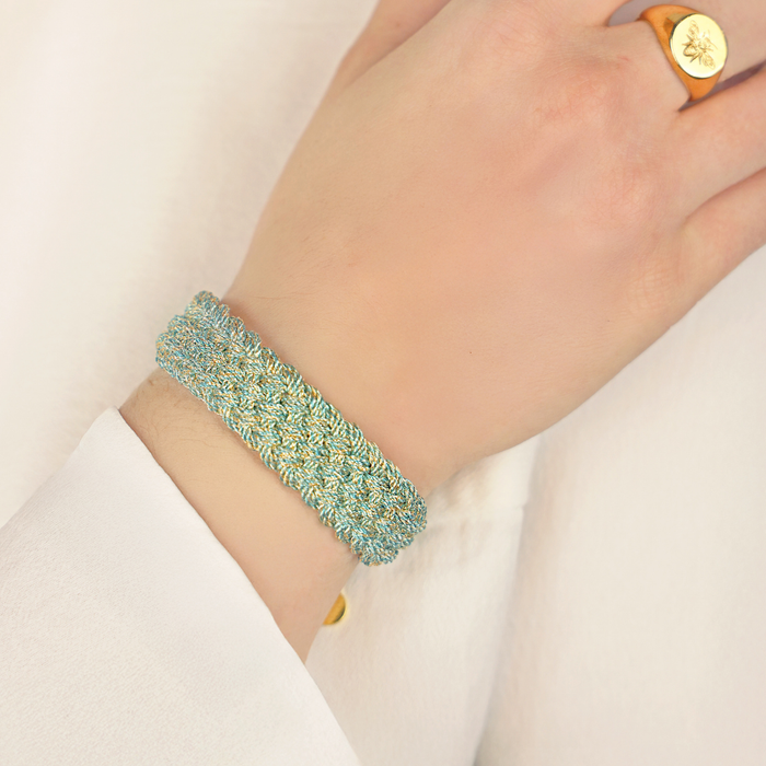 a hand wearing a gold ring and bracelet