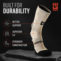 Military tan MudGear Ruck Sock displayed on angled surface showing cushioned sole, arch support band, and black heel/toe reinforcement