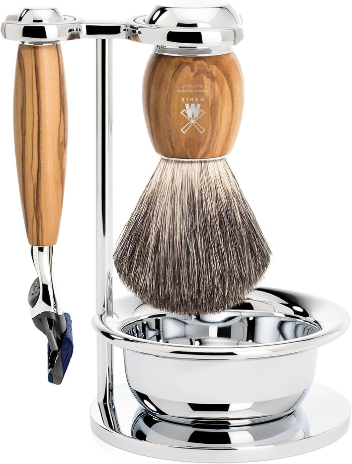 A 4-piece shaving set with a chrome-plated stand, olive wood handles, a pure badger brush, a Gillette Fusion razor, and a metal shaving bowl.