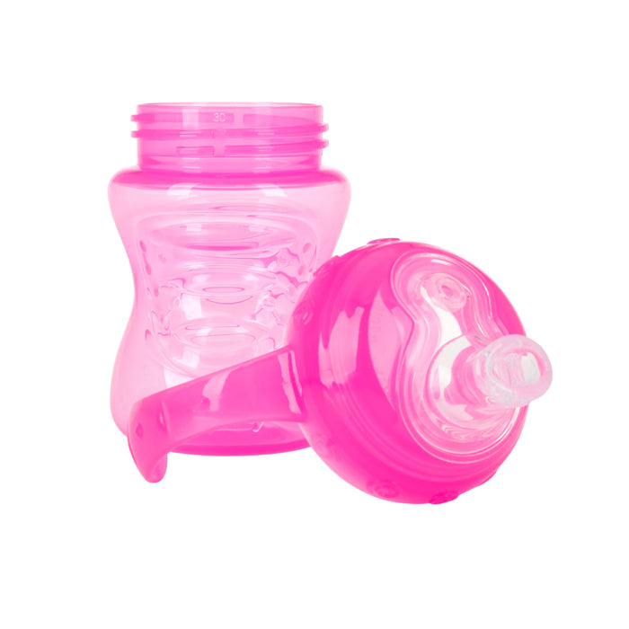 The Nuby No-Spill Soft Spout Grip N' Sip Trainer Cup, a pink plastic cup with a handle and silicone spout, is shown with its leak-resistant lid removed and placed in front against a white background.