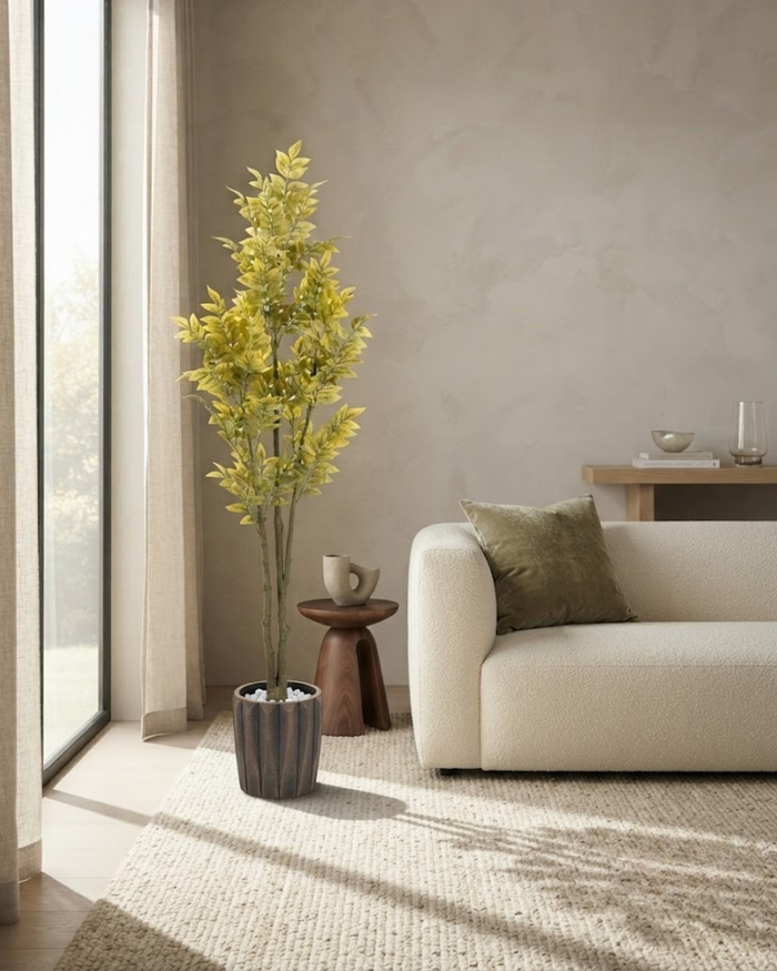 Tall artificial foliage plant in a dark textured planter near a window