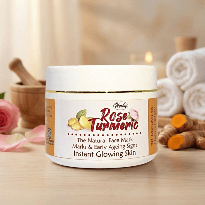 Herby Rose Turmeric face mask jar on a wooden table with roses, turmeric root, and towels for a natural glow.