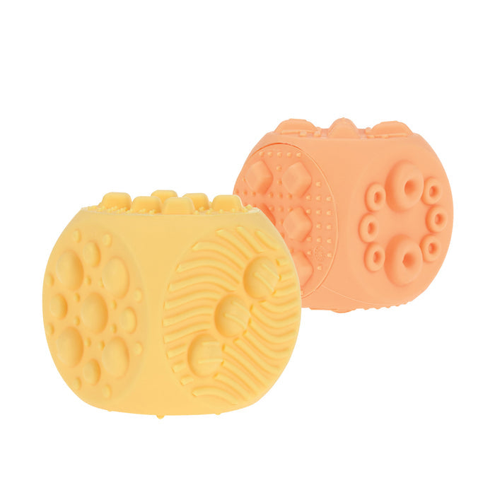 The Nuby US Silicone Popper Blocks (2 Pack) include yellow and peach textured sensory blocks with raised shapes like circles, dots, and lines—ideal baby toys for enhancing fine motor skills.