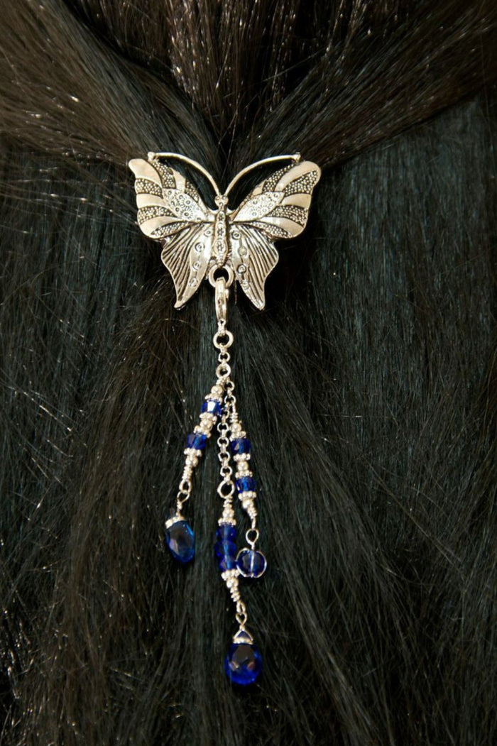Silver butterfly hair hook ponytail holder with dangling blue crystal bead charms worn in dark ponytail, back view
