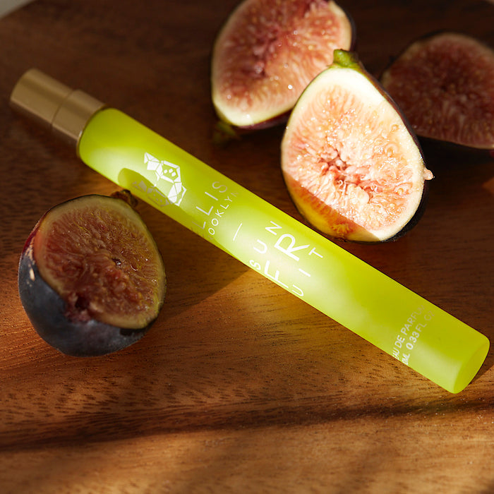 Sun Fruit 10ml Eau De Parfum Travel Spray on wooden table with figs.