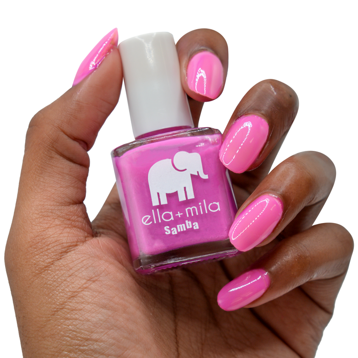 Sun Has Set hot pink nail polish on a deep skin tone, hand holding the bottle