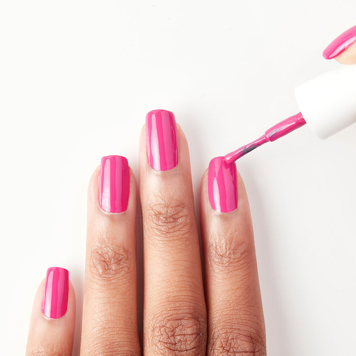 Applying Sun Has Set hot pink nail polish to the nails