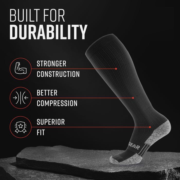 Tall compression sock in all black with gray heel and toe, shown on leg against dark background with durability callouts
