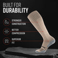 Coyote Tan tall compression socks displayed on stone, showing ribbed knit construction and gray heel reinforcement
