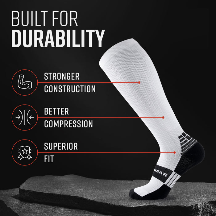 White tall compression sock with black foot and calf band on gray stone surface