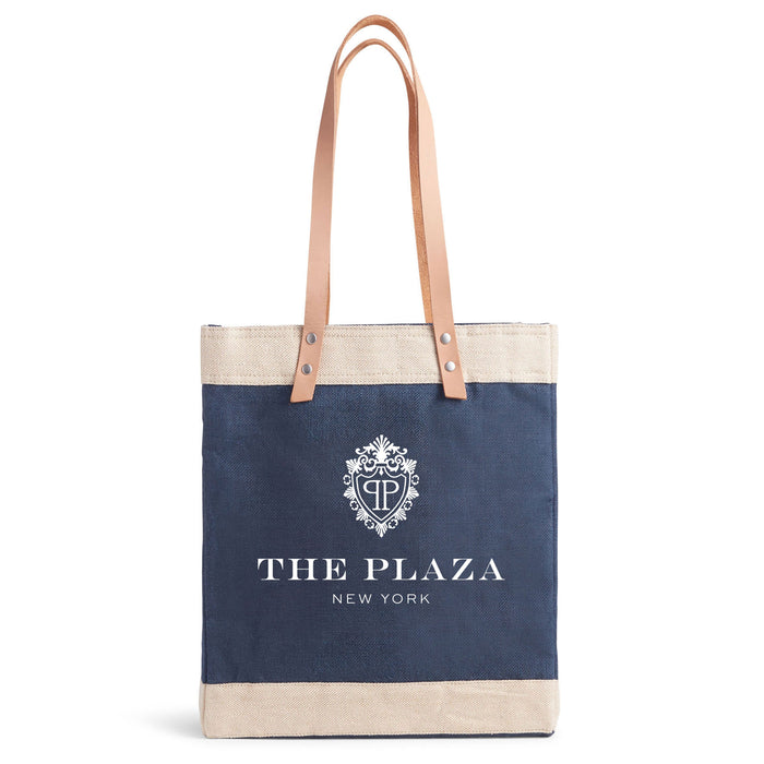 Navy tote bag with beige top handle and 'The Plaza New York' logo on a white background