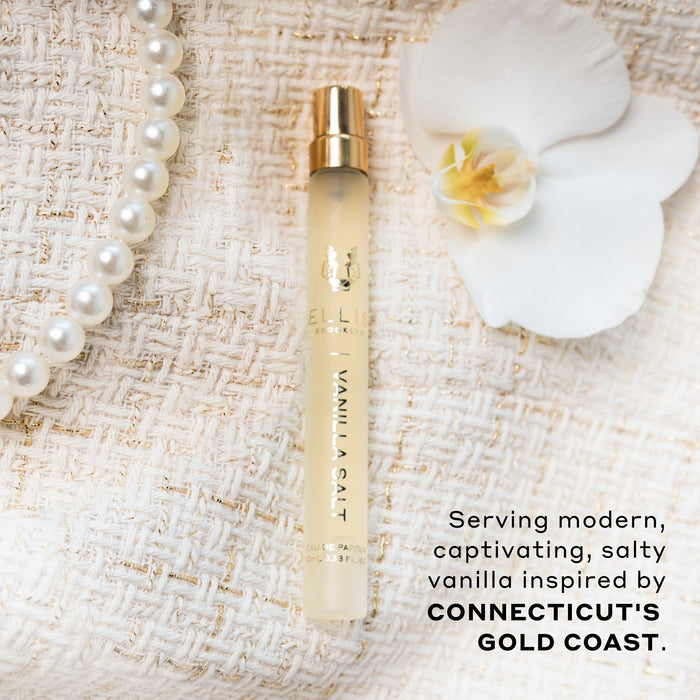 Vanilla Salt 10ml Eau De Parfum Travel Spray, white flower, and pearl necklace, on cream boucle fabric, above black text that reads "Serving modern, captivating, salty vanilla inspired by Connecticut's Gold Coast."