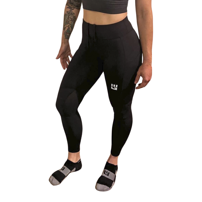 Woman wearing black full-length compression leggings with MudGear logo and black compression socks
